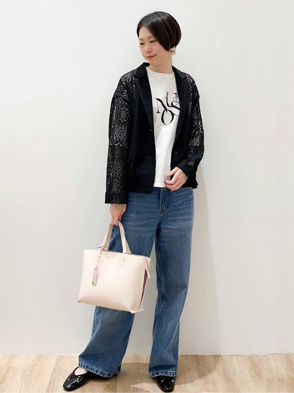 ブルー系のデニムパンツ、ブラック系のパンプス、ベージュ系のトートバッグを着用したレディースの春コーディネートの4枚目の写真