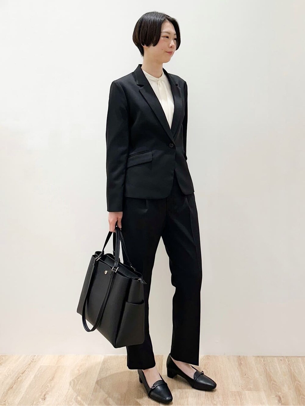 ブラック系のトートバッグ、ブラック系のパンプス、ホワイト系のシャツ/ブラウスを着用したレディースの春コーディネートの3枚目の写真