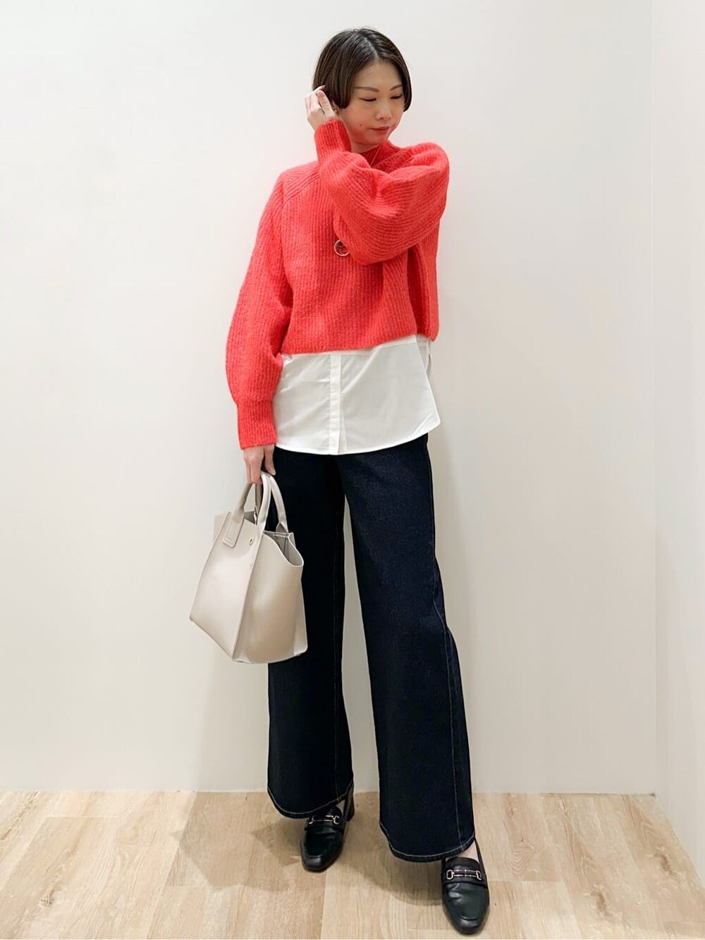 レッド系のニット/セーター、ホワイト系のTシャツ/カットソー、ブルー系のデニムパンツを着用したレディースの冬コーディネートの3枚目の写真