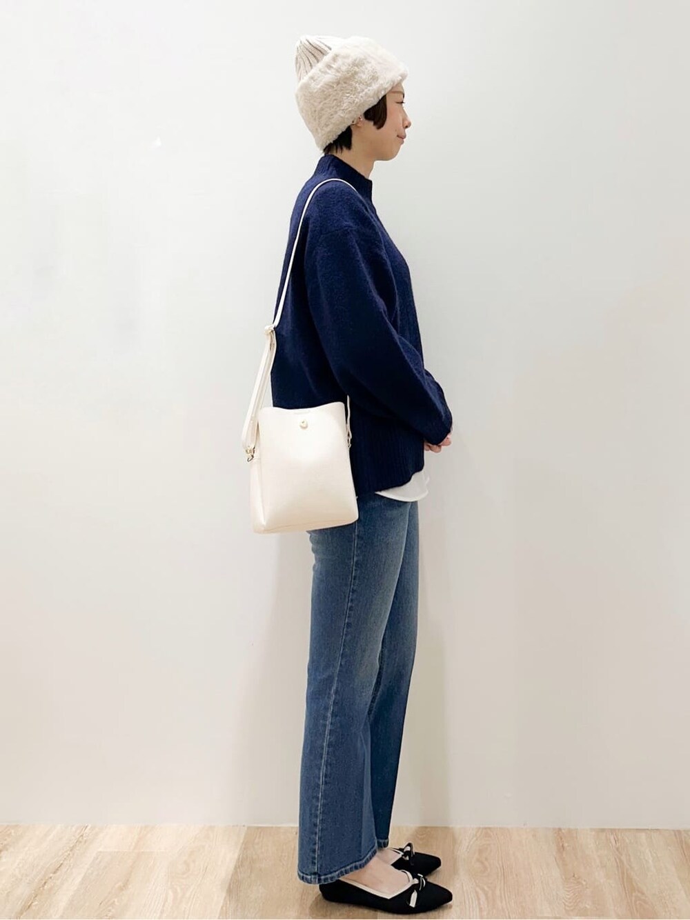 ブルー系のニット/セーター、ホワイト系のTシャツ/カットソー、ブルー系のデニムパンツを着用したレディースの冬コーディネートの4枚目の写真