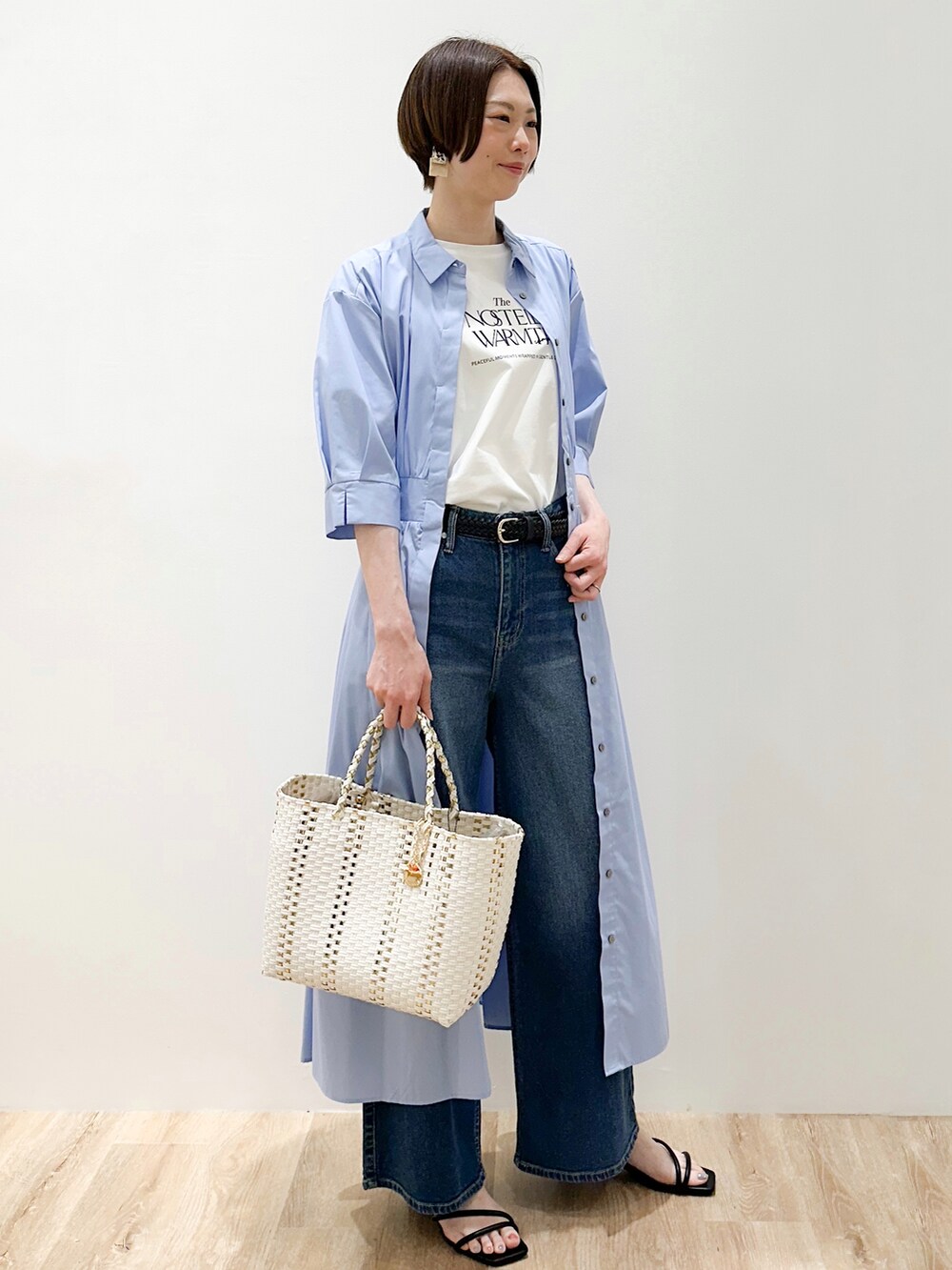 ブルー系のデニムパンツ、ブルー系のワンピース、ホワイト系のトートバッグを着用したレディースの春コーディネートの2枚目の写真