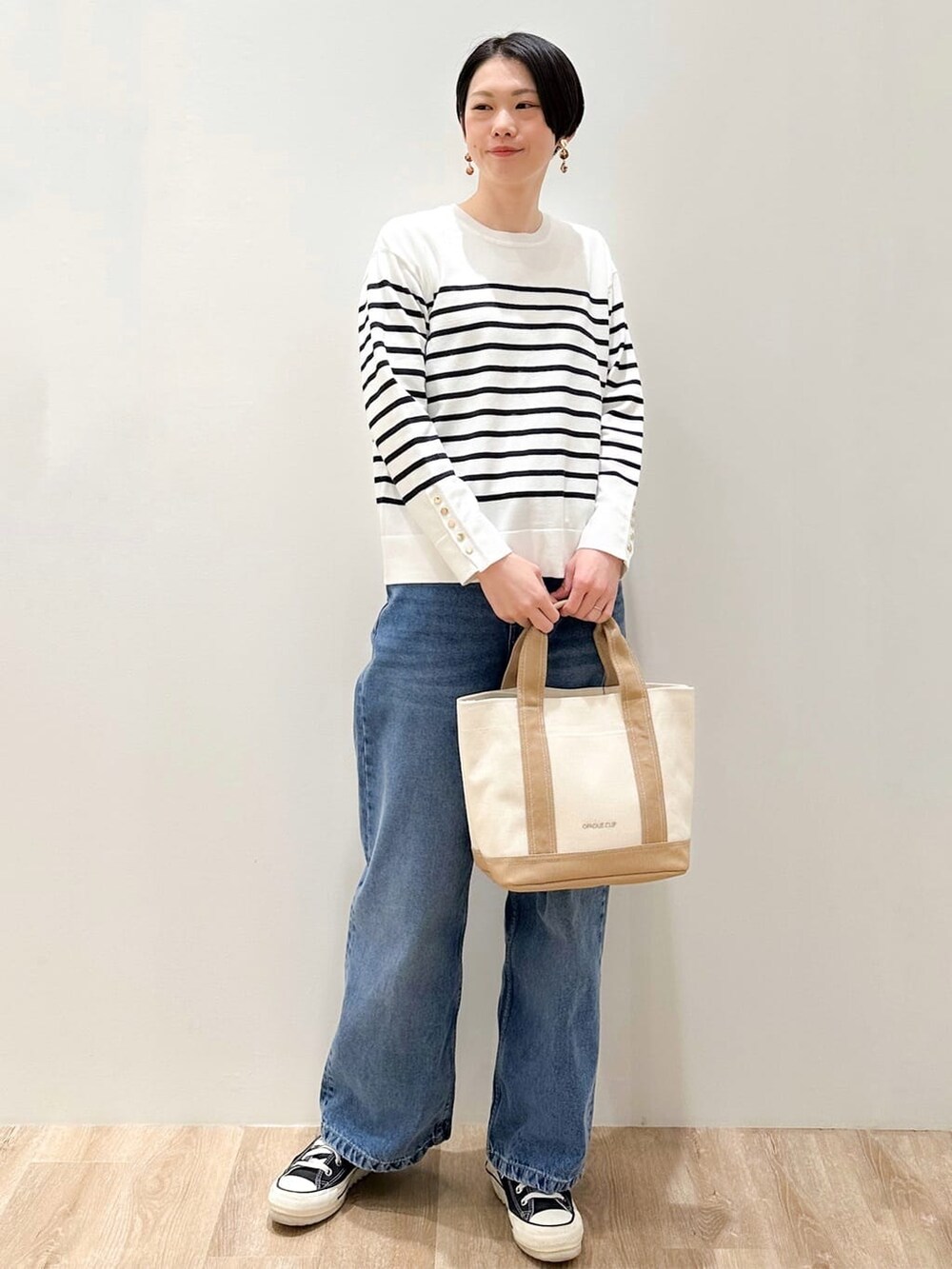 ホワイト系のニット/セーター、ブルー系のデニムパンツ、ベージュ系のトートバッグを着用したレディースの冬コーディネートの2枚目の写真