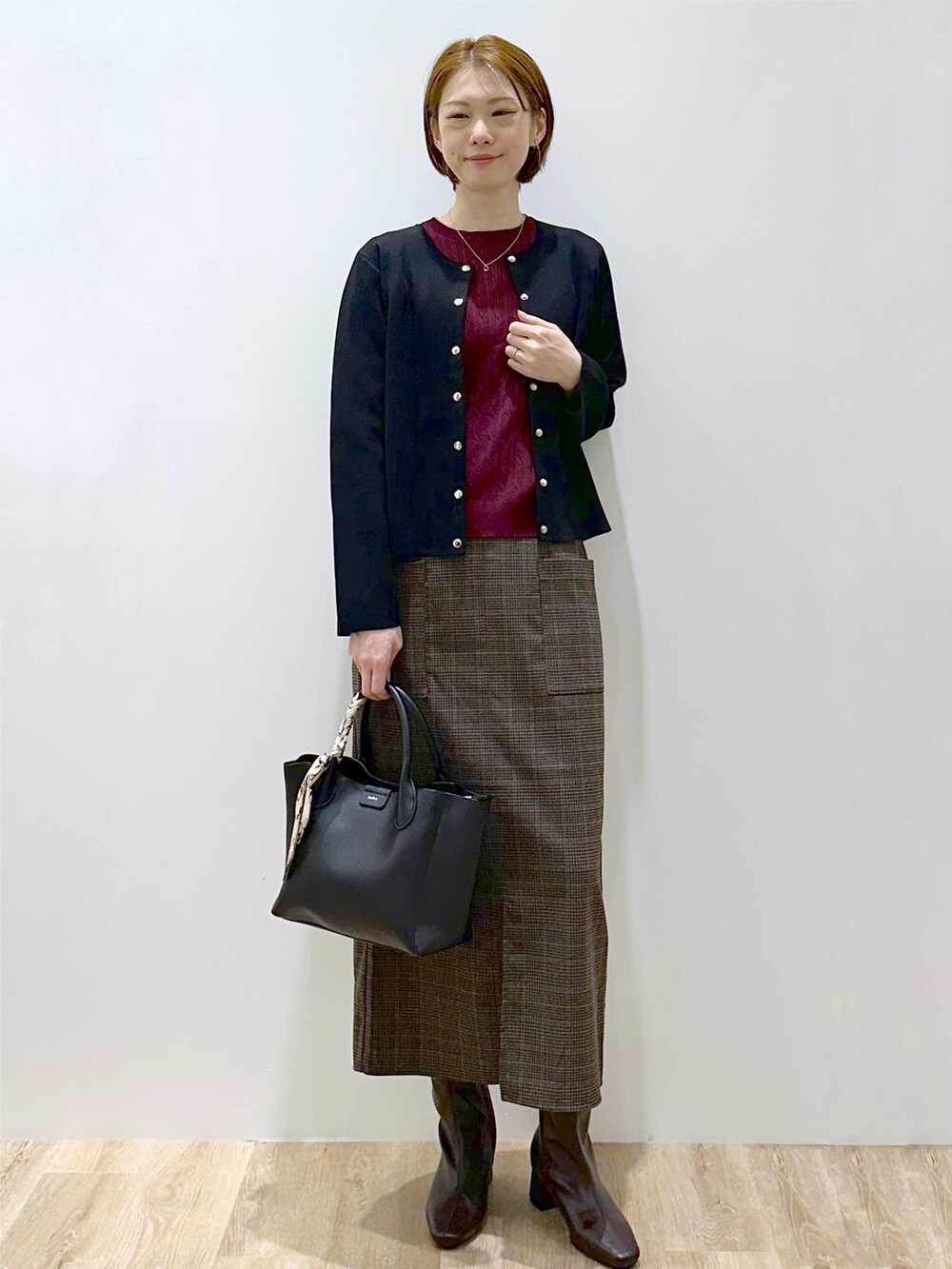 ブラック系のカーディガン/ボレロ、レッド系のニット/セーター、ブラック系のトートバッグを着用したレディースの秋コーディネートの6枚目の写真