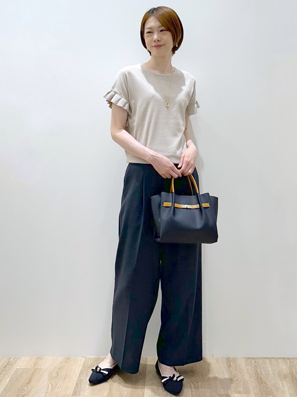 ベージュ系のニット/セーター、ブルー系のその他パンツ、ブルー系のトートバッグを着用したレディースの夏コーディネートの2枚目の写真