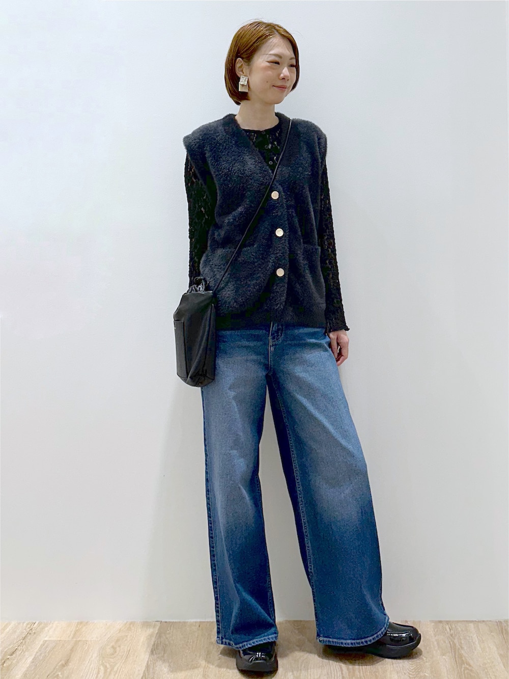 グレー系のニット/セーター、ブラック系のカーディガン/ボレロ、ブルー系のデニムパンツを着用したレディースの秋コーディネートの2枚目の写真