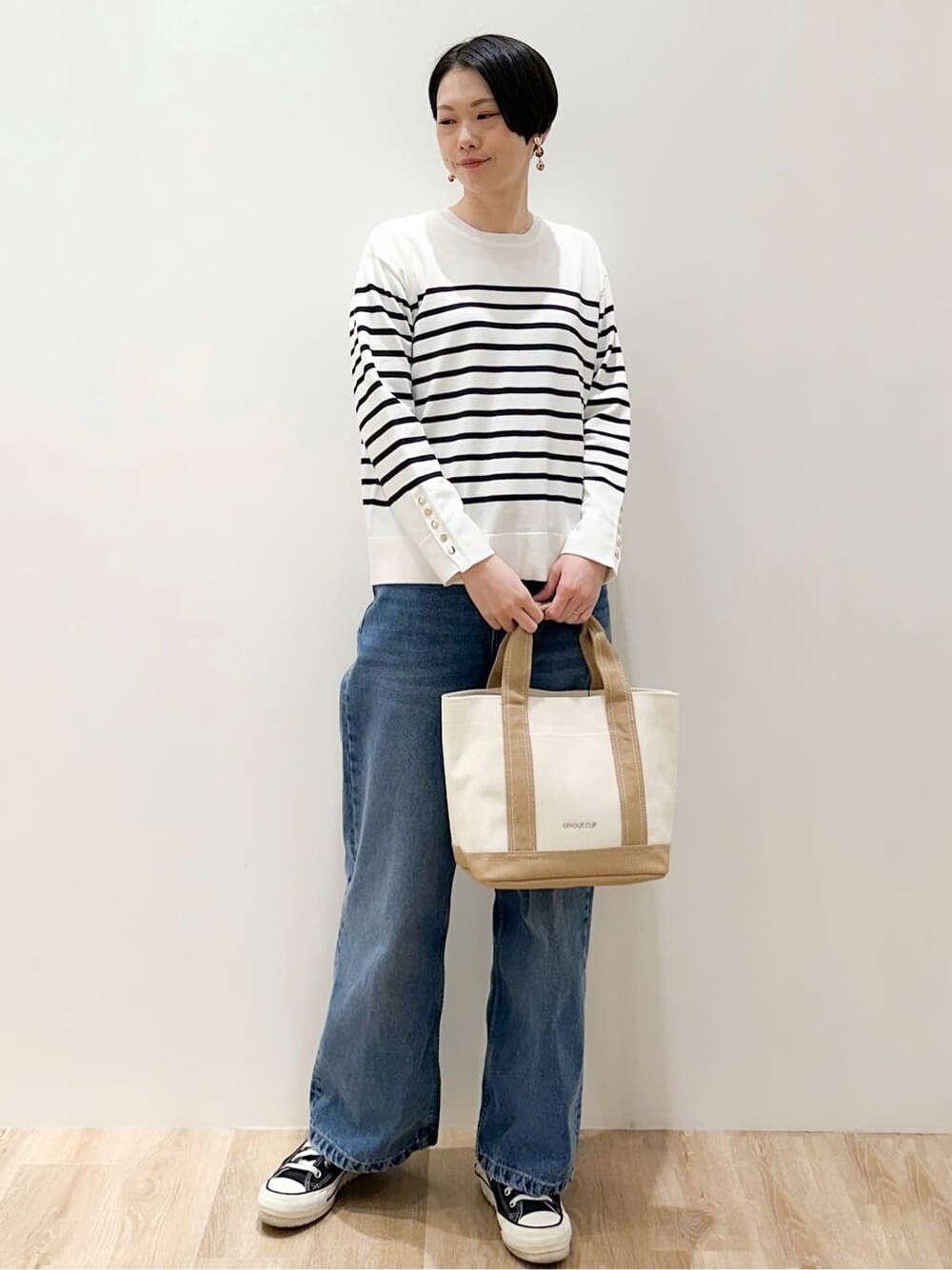 ホワイト系のニット/セーター、ブルー系のデニムパンツ、ベージュ系のトートバッグを着用したレディースの冬コーディネートの5枚目の写真