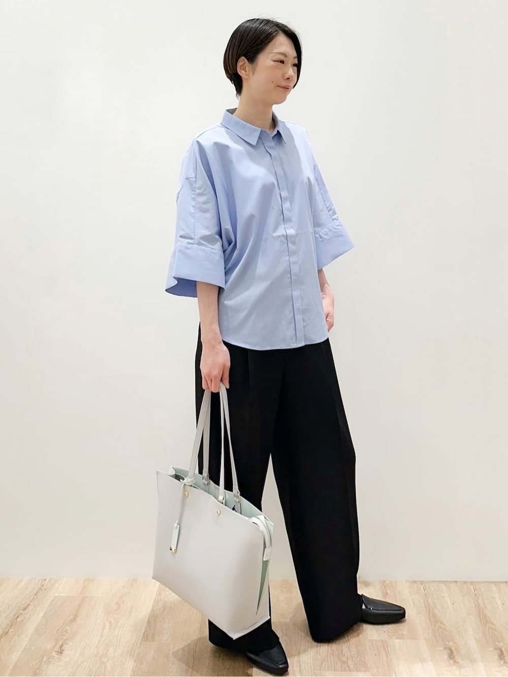 グレー系のトートバッグ、ブルー系のシャツ/ブラウス、ブラック系のその他パンツを着用したレディースの春コーディネートの3枚目の写真