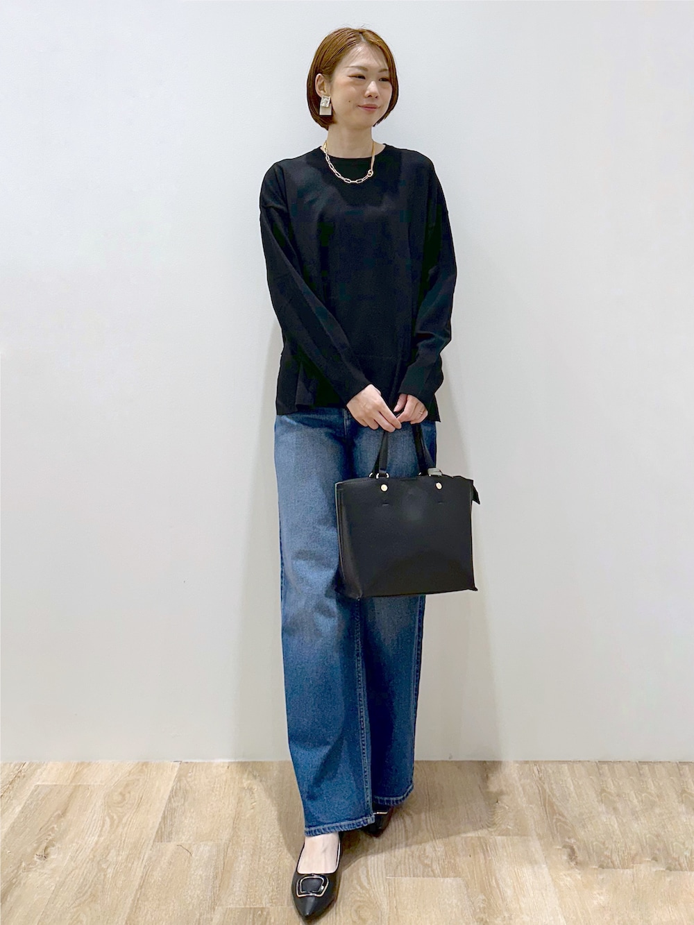 ブラック系のニット/セーター、ブルー系のデニムパンツ、ブラック系のトートバッグを着用したレディースの秋コーディネートの2枚目の写真