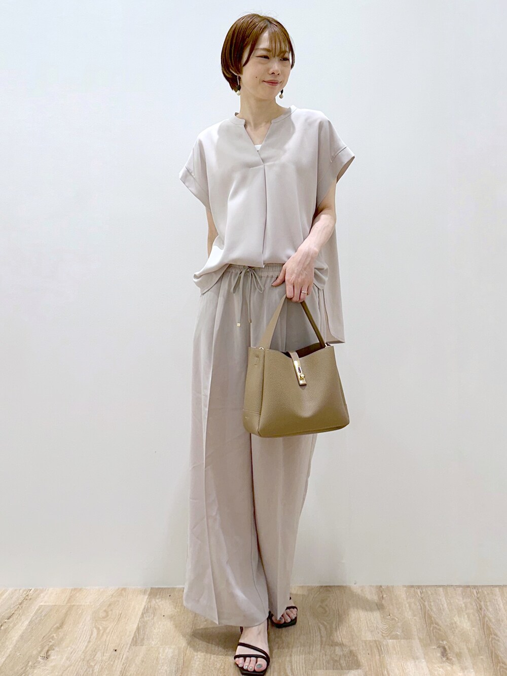 ベージュ系のシャツ/ブラウス、ベージュ系のその他パンツ、ブラウン系のトートバッグを着用したレディースの夏コーディネートの2枚目の写真