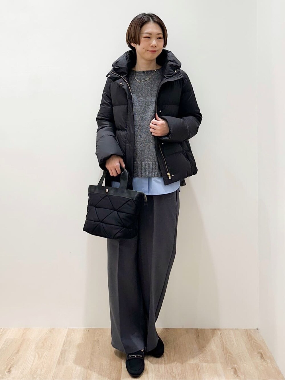 ブラック系のダウンジャケット/コート、グレー系のニット/セーター、ブルー系のTシャツ/カットソーを着用したレディースの冬コーディネートの6枚目の写真