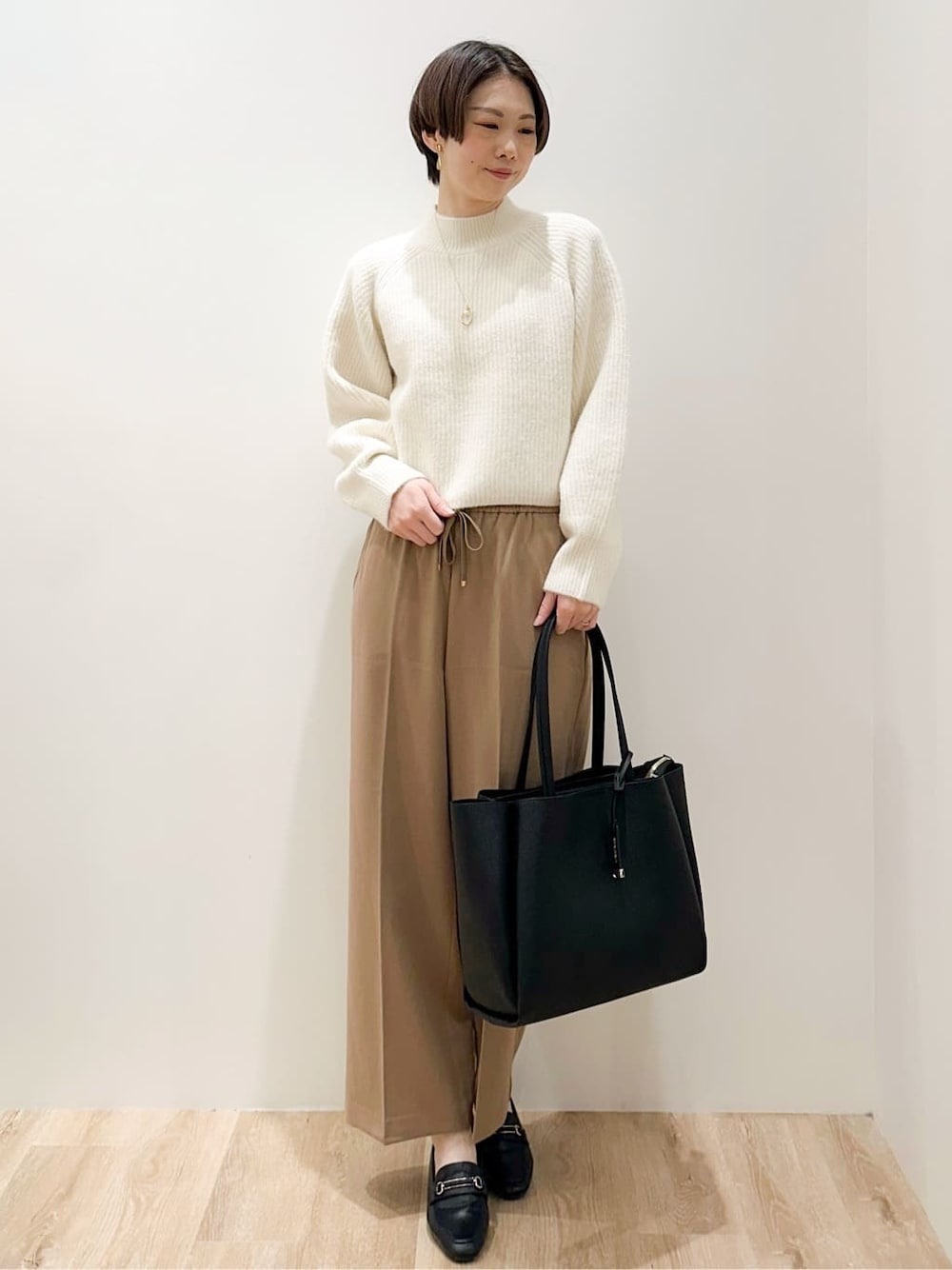 ホワイト系のニット/セーター、イエロー系のその他パンツ、ブラック系のトートバッグを着用したレディースの冬コーディネートの4枚目の写真