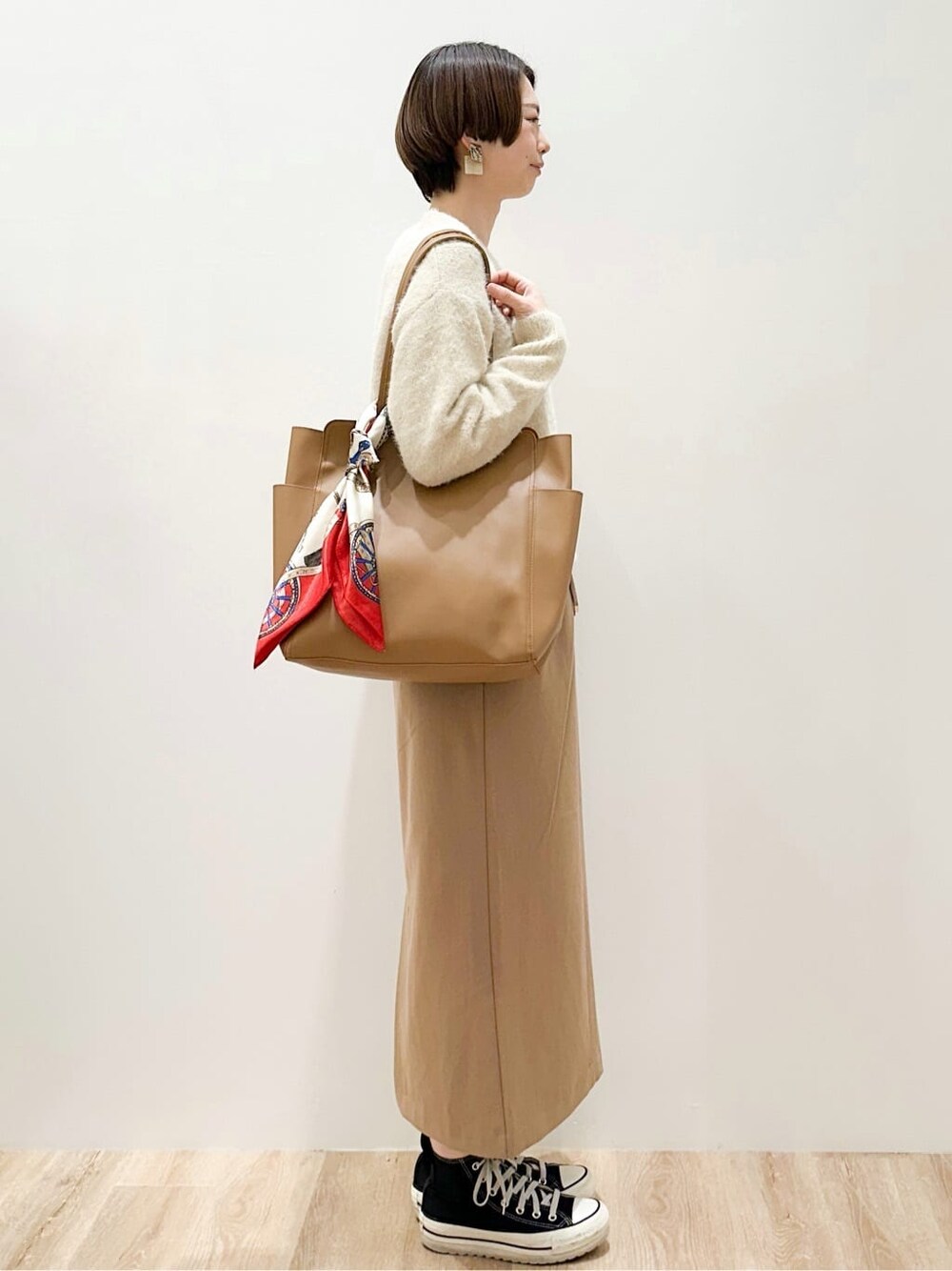 ベージュ系のニット/セーター、イエロー系のスカート、ベージュ系のトートバッグを着用したレディースの冬コーディネートの2枚目の写真