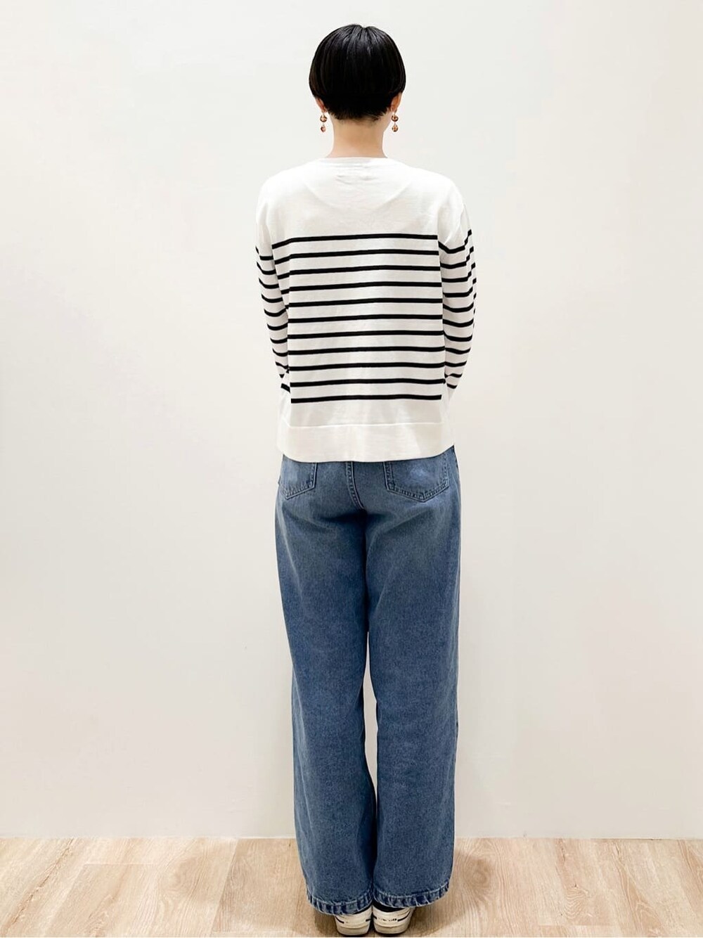 ホワイト系のニット/セーター、ブルー系のデニムパンツ、ベージュ系のトートバッグを着用したレディースの冬コーディネートの4枚目の写真