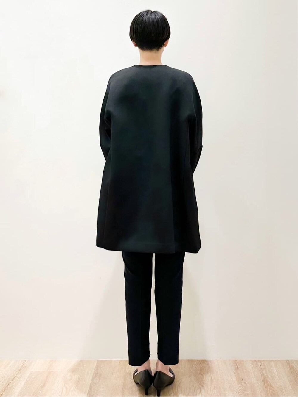 ブラック系のノーカラーコート、ホワイト系のシャツ/ブラウス、ブラック系のその他パンツを着用したレディースの冬コーディネートの4枚目の写真