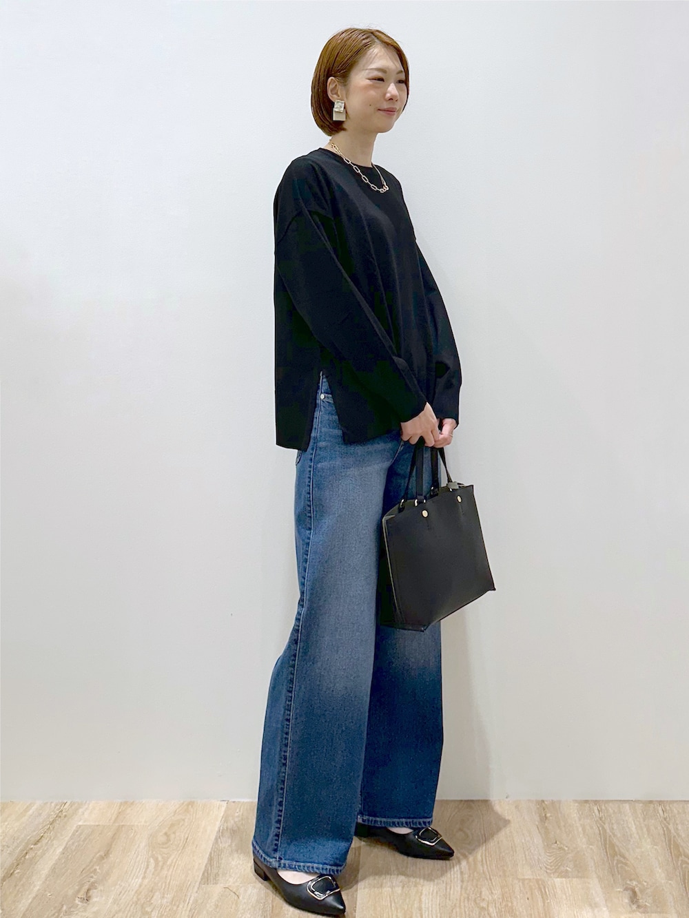 ブラック系のニット/セーター、ブルー系のデニムパンツ、ブラック系のトートバッグを着用したレディースの秋コーディネートの3枚目の写真