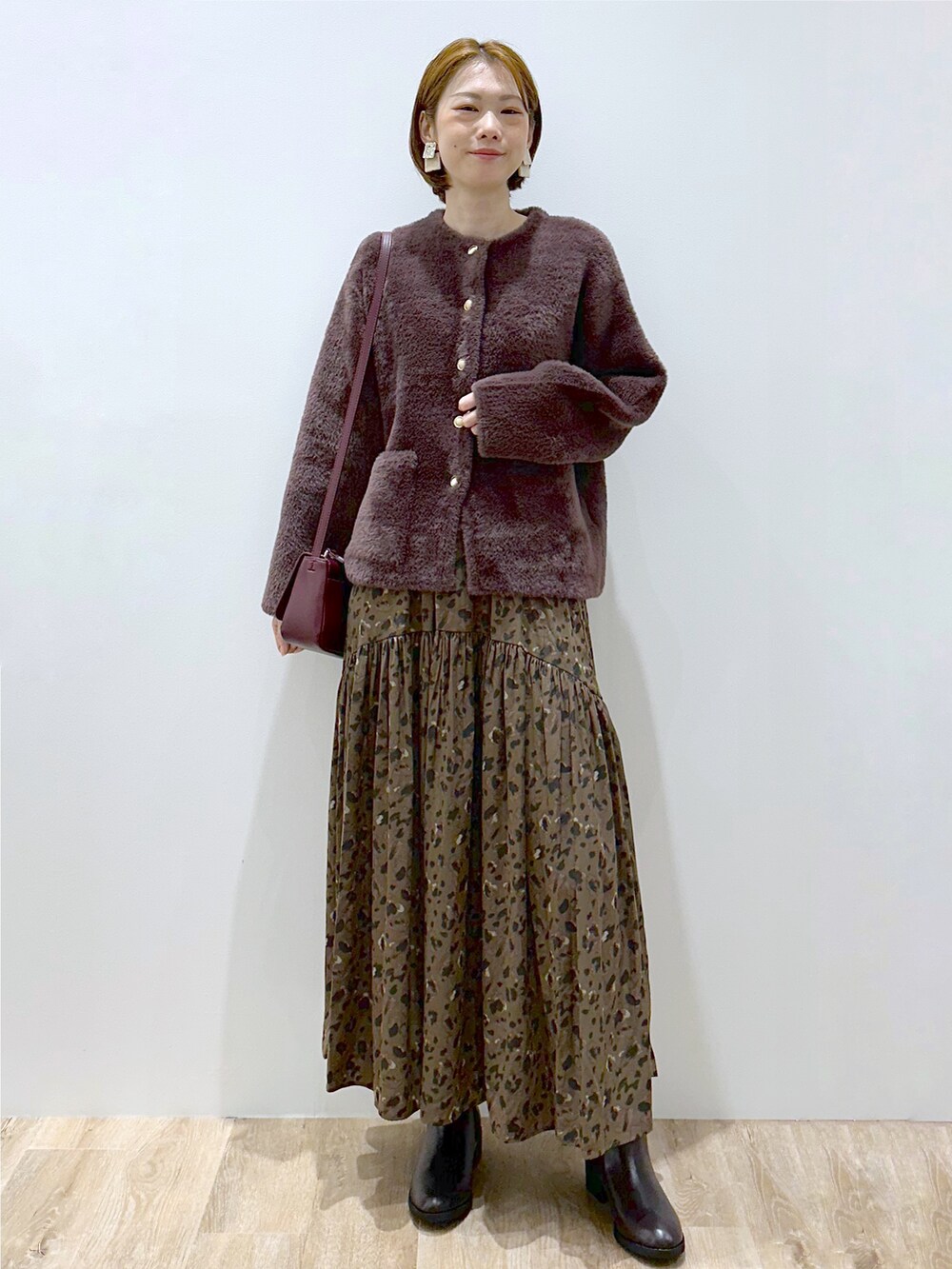 ブラウン系のカーディガン/ボレロ、ブラウン系のスカート、レッド系のショルダーバッグを着用したレディースの秋コーディネートの6枚目の写真