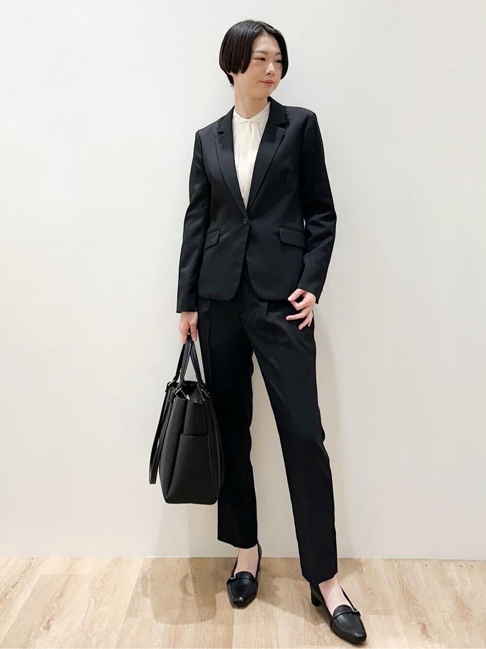ブラック系のトートバッグ、ブラック系のパンプス、ホワイト系のシャツ/ブラウスを着用したレディースの春コーディネートの6枚目の写真