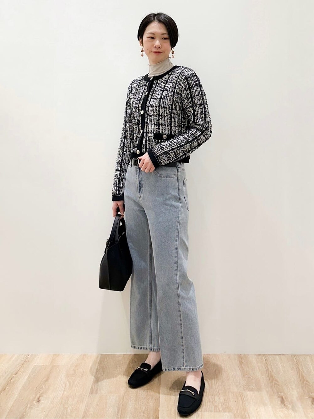 ブラック系のカーディガン/ボレロ、グレー系のTシャツ/カットソー、ブルー系のデニムパンツを着用したレディースの冬コーディネートの2枚目の写真