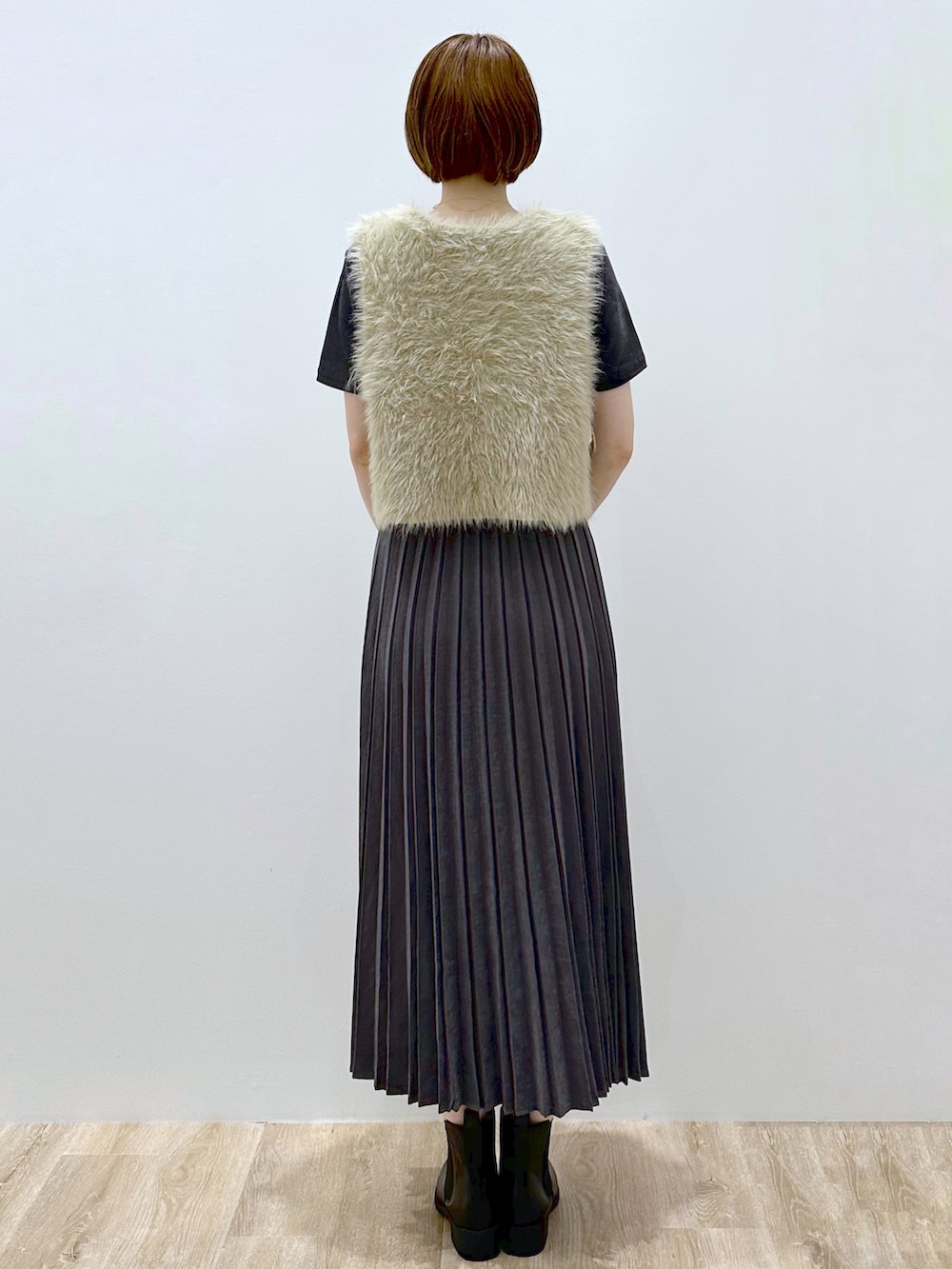 ベージュ系のベスト、グレー系のTシャツ/カットソー、グレー系のスカートを着用したレディースの秋コーディネートの5枚目の写真