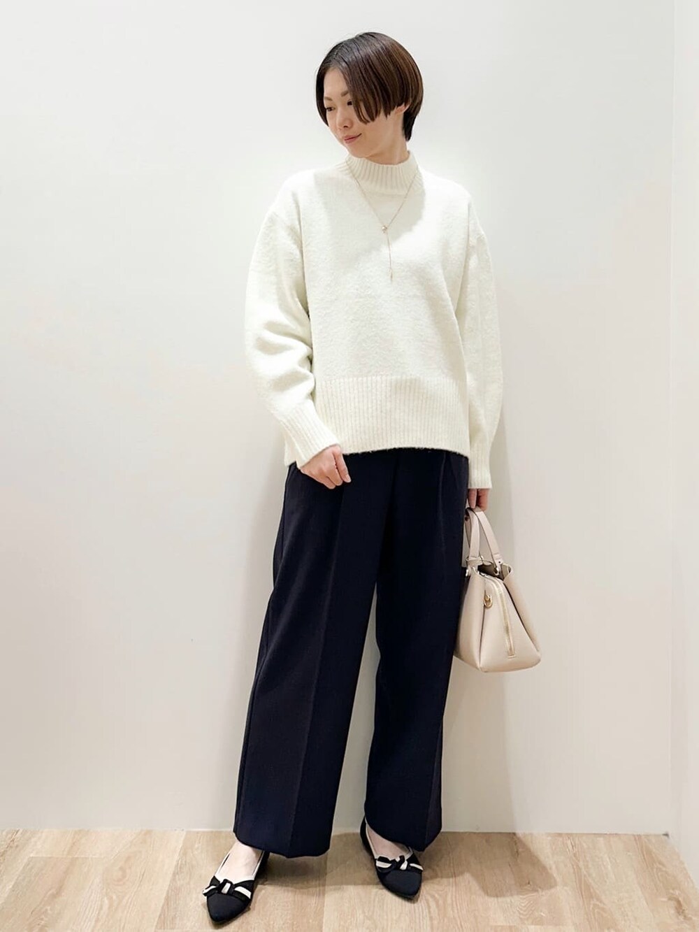 ホワイト系のニット/セーター、ブラック系のその他パンツ、ベージュ系のボストンバッグを着用したレディースの冬コーディネートの6枚目の写真