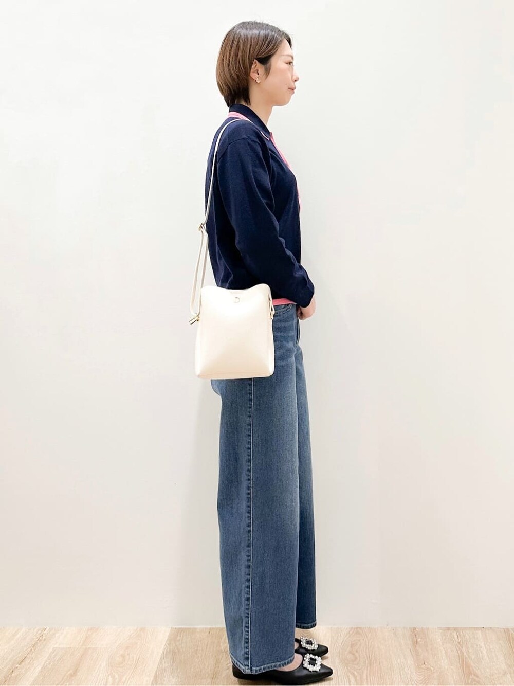 ブルー系のニット/セーター、ブルー系のデニムパンツ、ホワイト系のショルダーバッグを着用したレディースの冬コーディネートの2枚目の写真