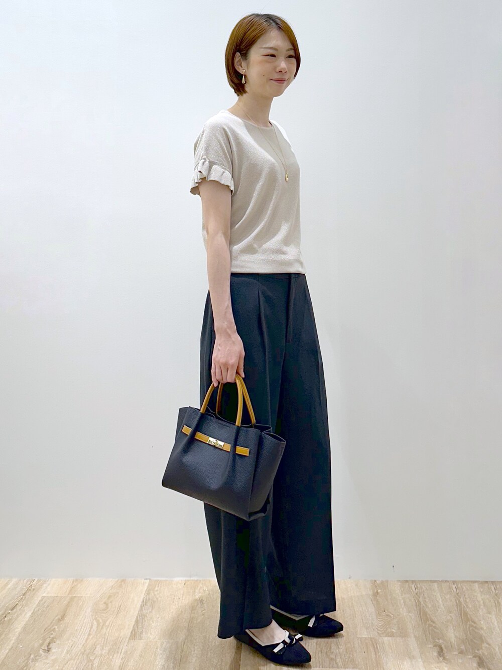 ベージュ系のニット/セーター、ブルー系のその他パンツ、ブルー系のトートバッグを着用したレディースの夏コーディネートの3枚目の写真