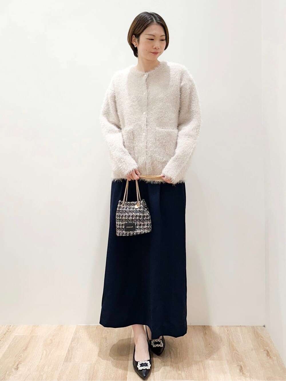 ホワイト系のカーディガン/ボレロ、ブルー系のスカート、ブラック系のショルダーバッグを着用したレディースの冬コーディネートの5枚目の写真