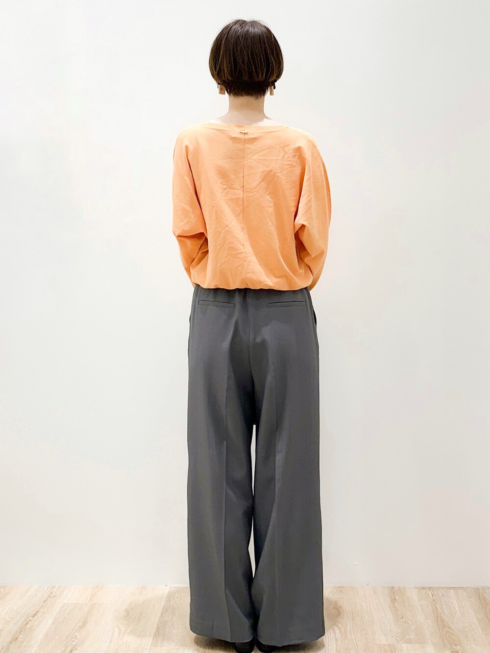 オレンジ系のニット/セーター、グレー系のその他パンツ、ブラック系のトートバッグを着用したレディースの春コーディネートの4枚目の写真