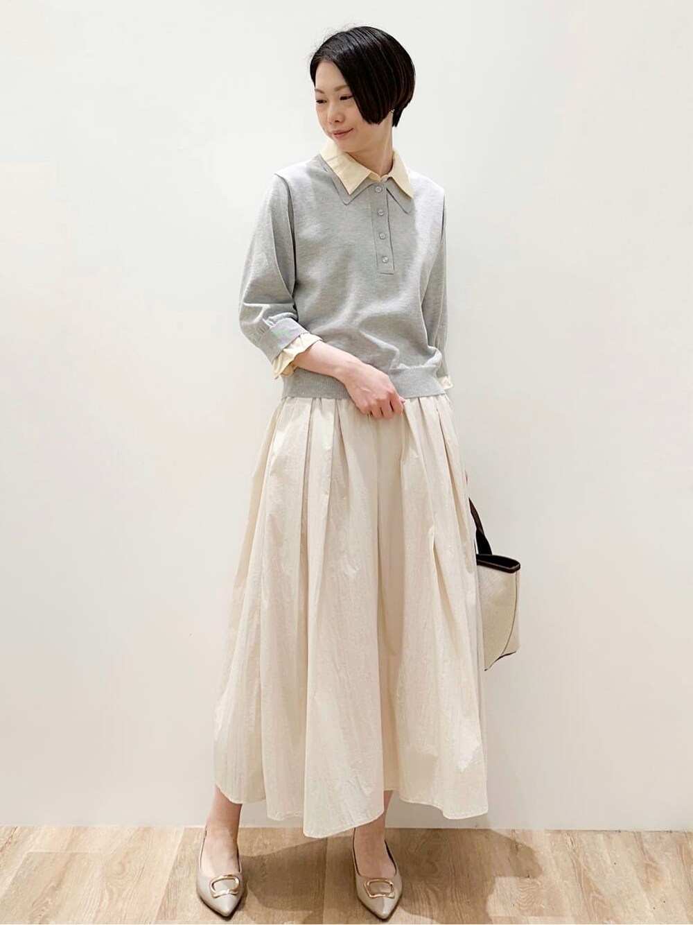 ベージュ系のパンプス、ベージュ系のスカート、ブラウン系のトートバッグを着用したレディースの春コーディネートの2枚目の写真