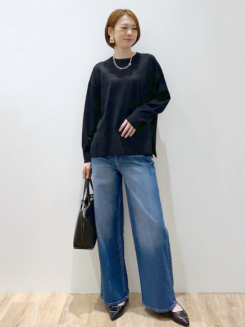 ブラック系のニット/セーター、ブルー系のデニムパンツ、ブラック系のトートバッグを着用したレディースの秋コーディネートの6枚目の写真