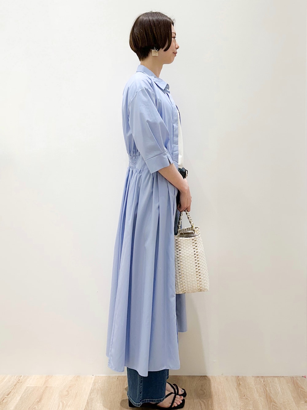ブルー系のデニムパンツ、ブルー系のワンピース、ホワイト系のトートバッグを着用したレディースの春コーディネートの3枚目の写真