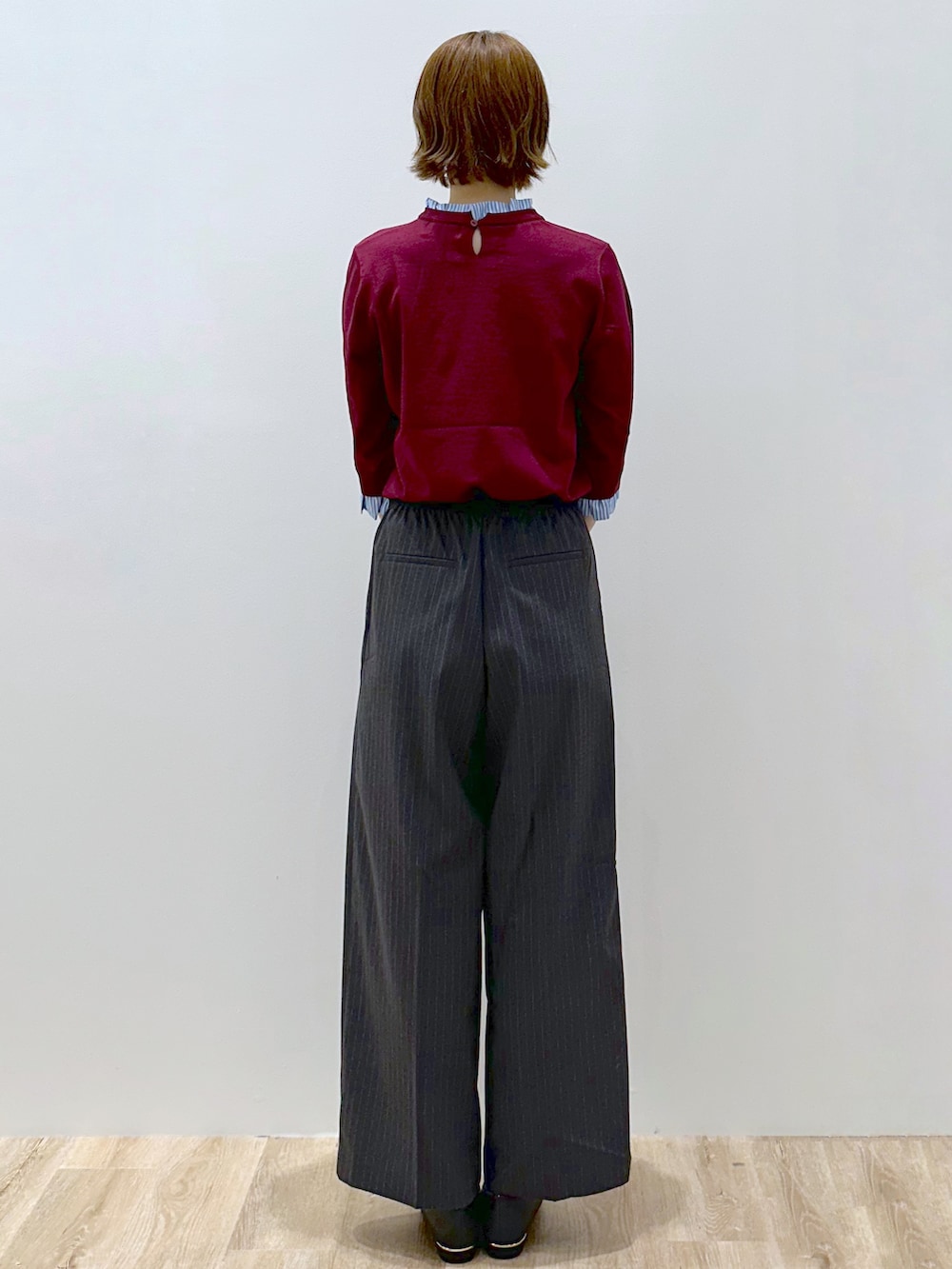 レッド系のニット/セーター、グレー系のその他パンツ、ブラック系のトートバッグを着用したレディースの秋コーディネートの4枚目の写真