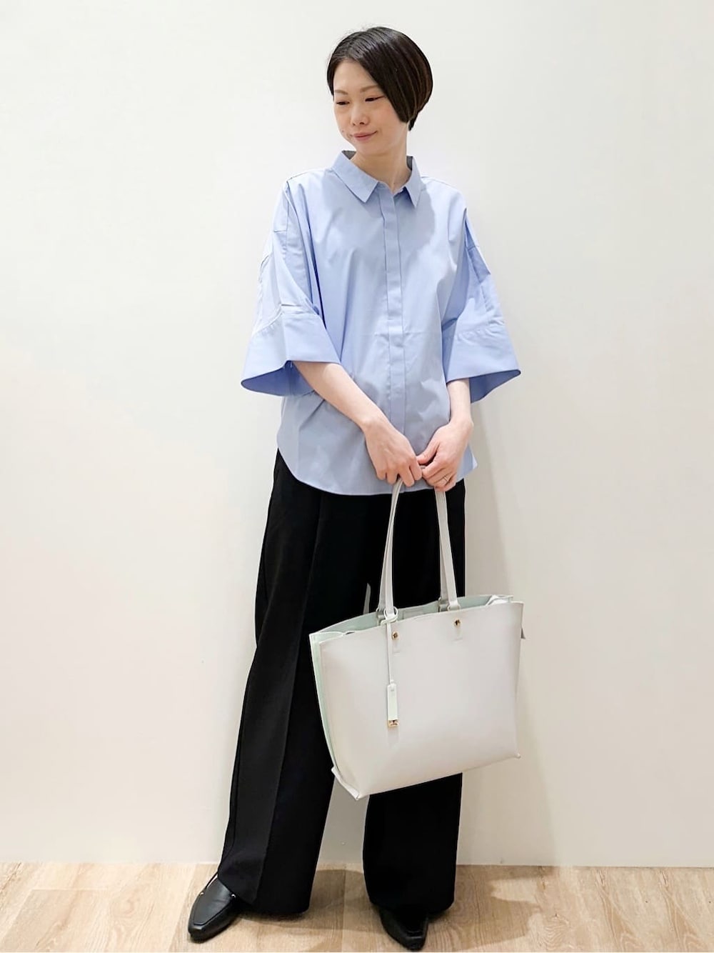 グレー系のトートバッグ、ブルー系のシャツ/ブラウス、ブラック系のその他パンツを着用したレディースの春コーディネートの2枚目の写真