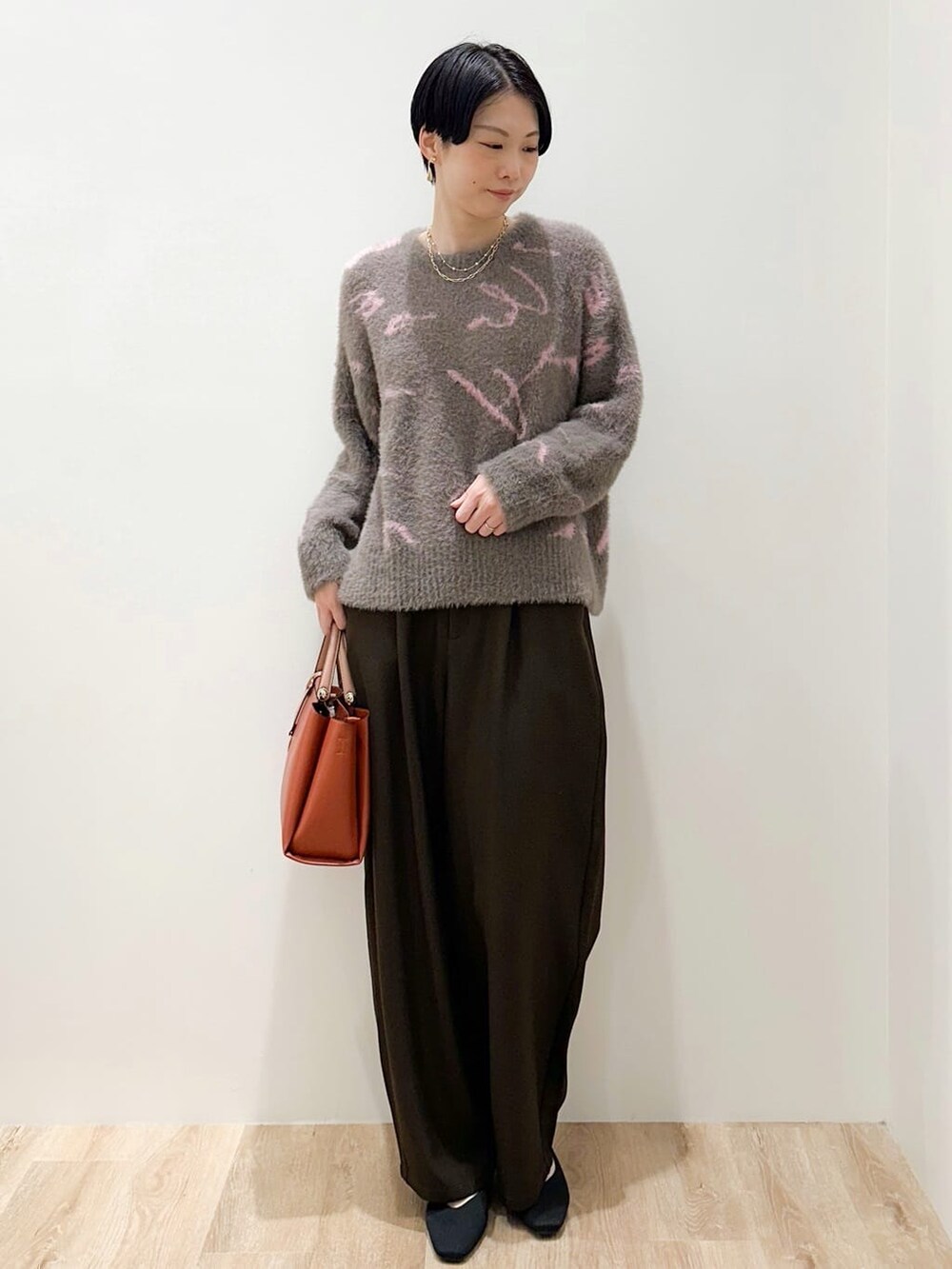 グレー系のニット/セーター、ブラウン系のその他パンツ、オレンジ系のトートバッグを着用したレディースの冬コーディネートの4枚目の写真