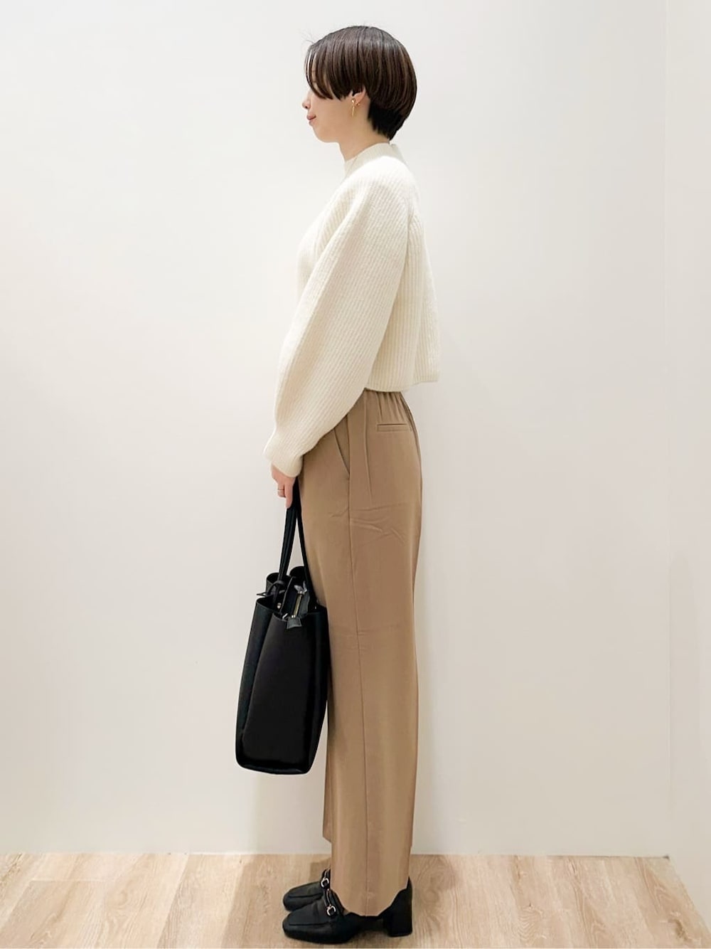 ホワイト系のニット/セーター、イエロー系のその他パンツ、ブラック系のトートバッグを着用したレディースの冬コーディネートの2枚目の写真
