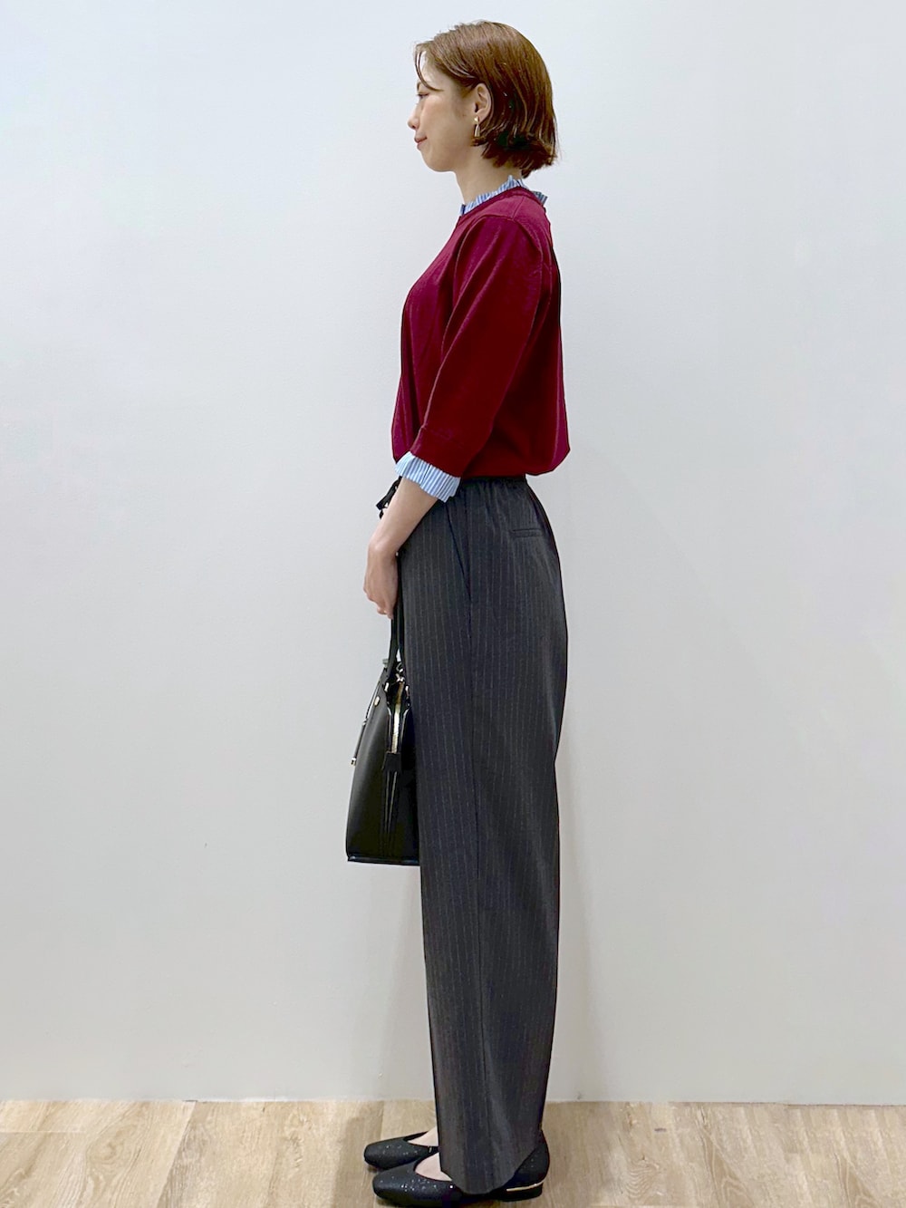 レッド系のニット/セーター、グレー系のその他パンツ、ブラック系のトートバッグを着用したレディースの秋コーディネートの5枚目の写真
