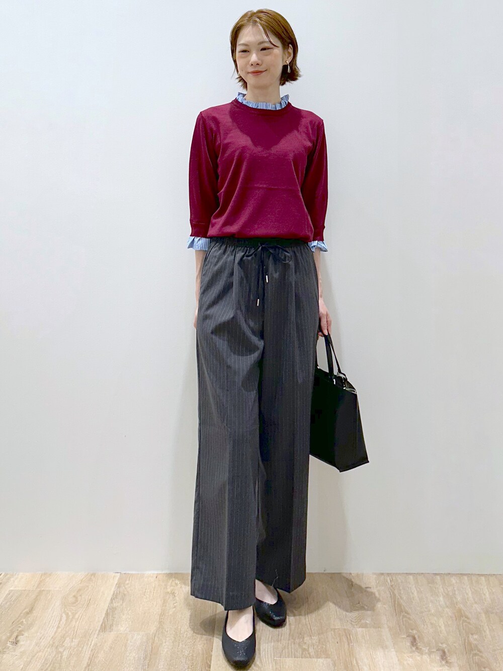 レッド系のニット/セーター、グレー系のその他パンツ、ブラック系のトートバッグを着用したレディースの秋コーディネートの6枚目の写真
