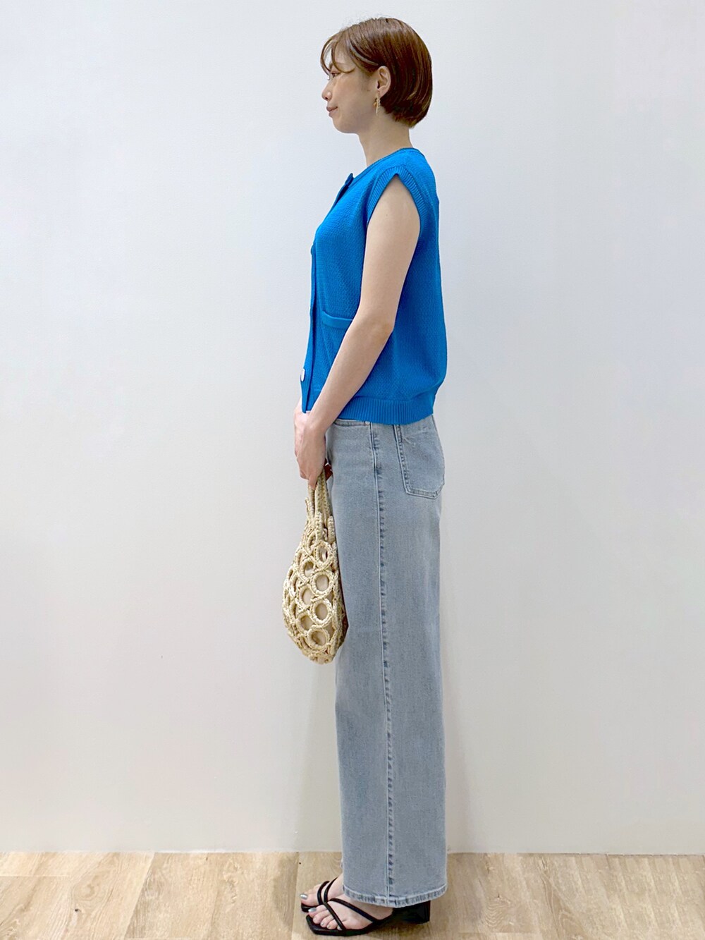 ブルー系のニット/セーター、ブルー系のデニムパンツ、ホワイト系のハンドバッグを着用したレディースの夏コーディネートの3枚目の写真