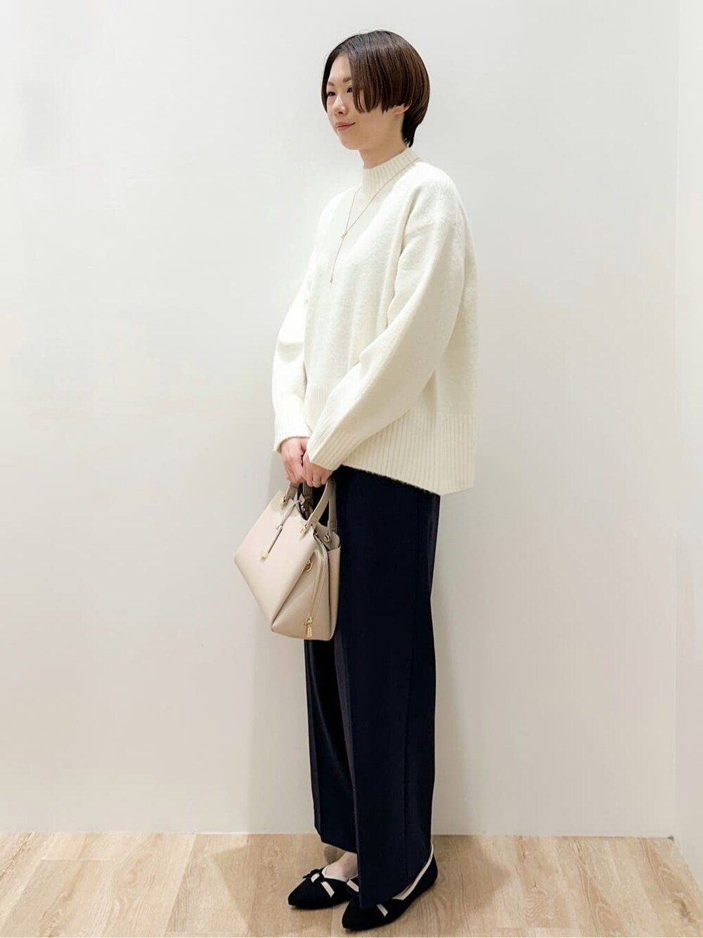 ホワイト系のニット/セーター、ブラック系のその他パンツ、ベージュ系のボストンバッグを着用したレディースの冬コーディネートの3枚目の写真
