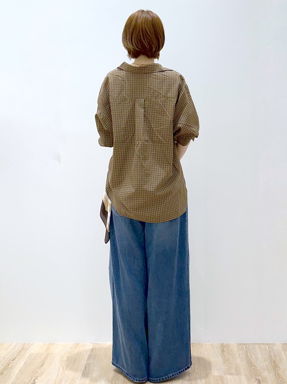 ブラウン系のシャツ/ブラウス、ブラック系のタンクトップ、ブルー系のデニムパンツを着用したレディースの秋コーディネートの4枚目の写真
