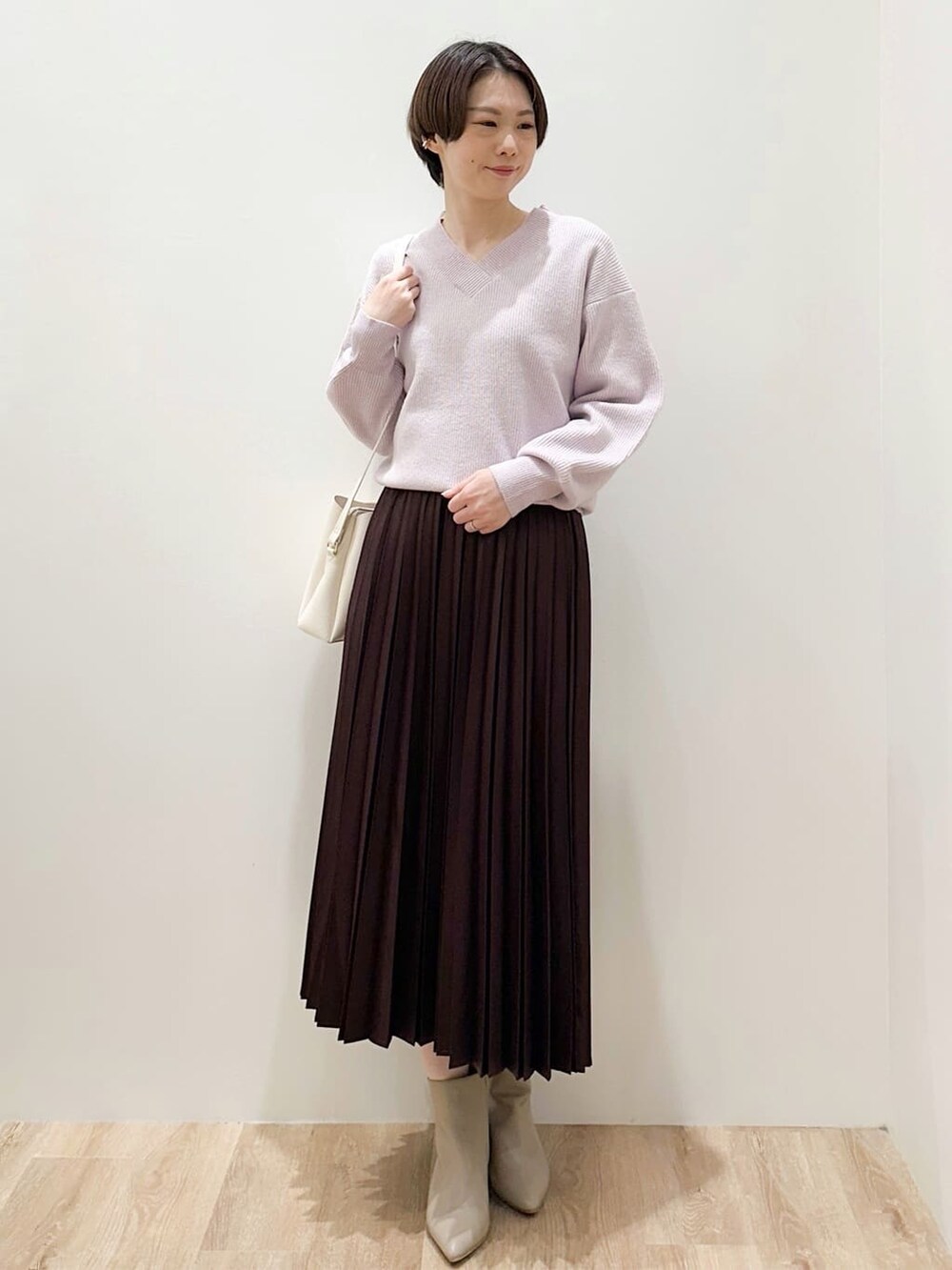 ピンク系のニット/セーター、レッド系のスカート、ホワイト系のショルダーバッグを着用したレディースの冬コーディネートの4枚目の写真