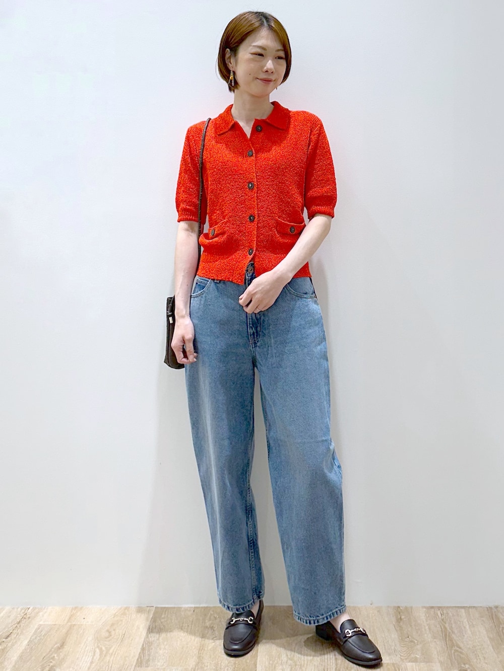 レッド系のカーディガン/ボレロ、ブルー系のデニムパンツ、ブラウン系のショルダーバッグを着用したレディースの夏コーディネートの7枚目の写真