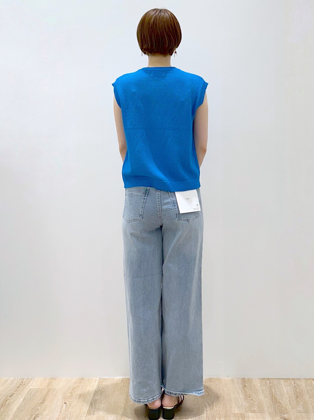 ブルー系のニット/セーター、ブルー系のデニムパンツ、ホワイト系のハンドバッグを着用したレディースの夏コーディネートの4枚目の写真