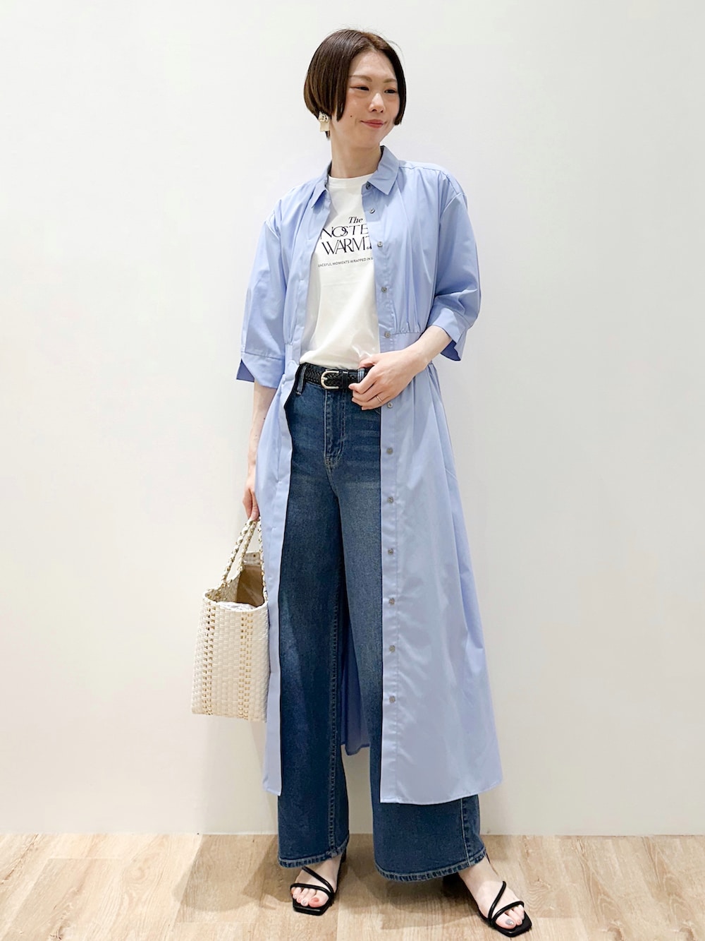 ブルー系のデニムパンツ、ブルー系のワンピース、ホワイト系のトートバッグを着用したレディースの春コーディネートの5枚目の写真