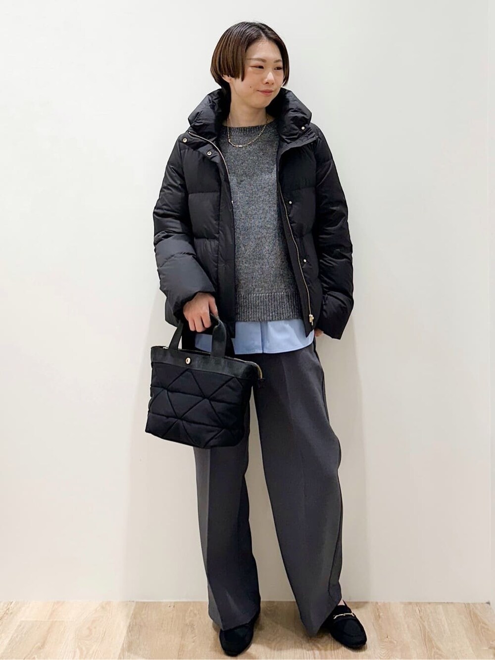 ブラック系のダウンジャケット/コート、グレー系のニット/セーター、ブルー系のTシャツ/カットソーを着用したレディースの冬コーディネートの5枚目の写真