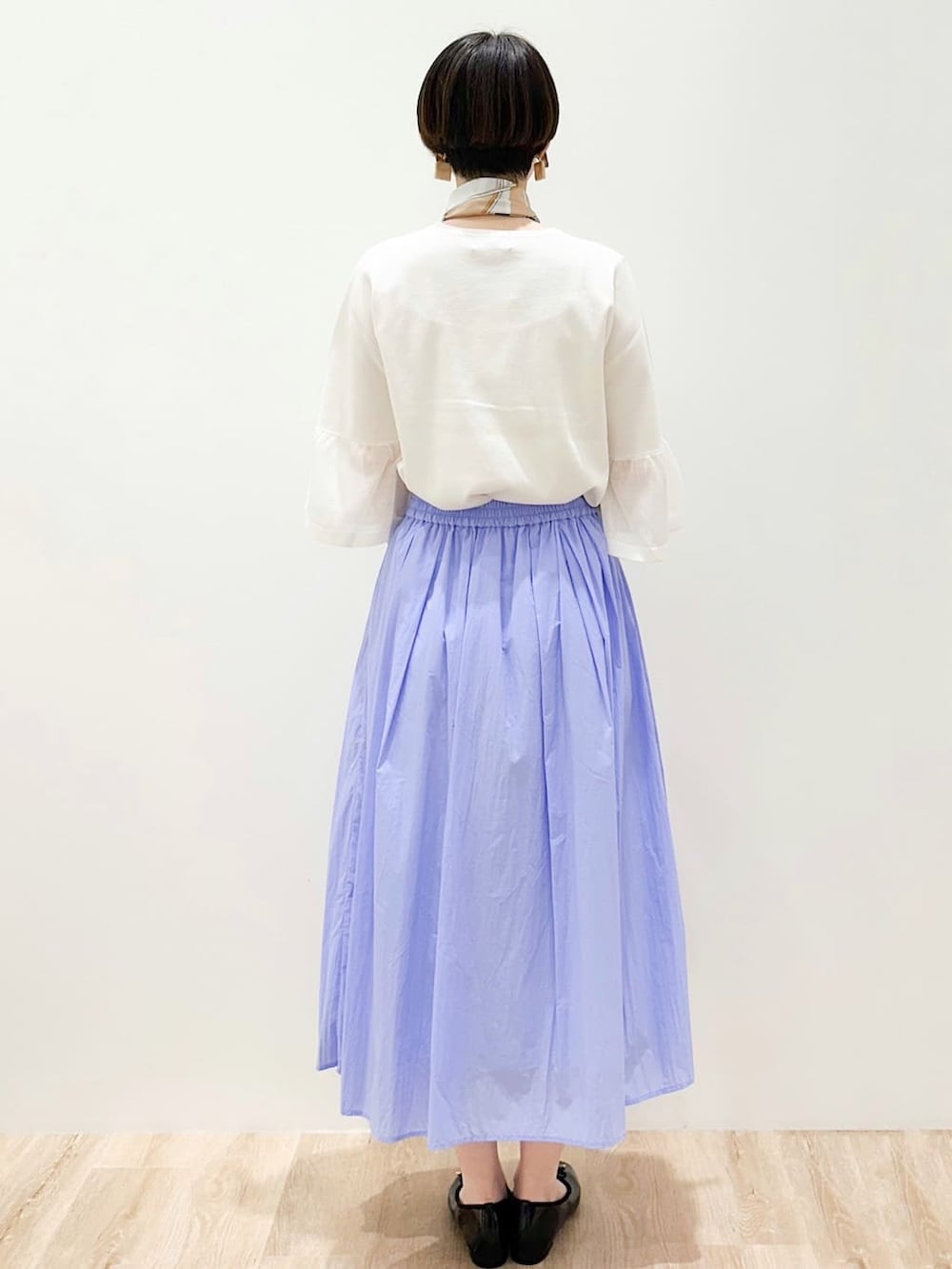 ブラック系のパンプス、ブルー系のスカート、グレー系のトートバッグを着用したレディースの春コーディネートの4枚目の写真