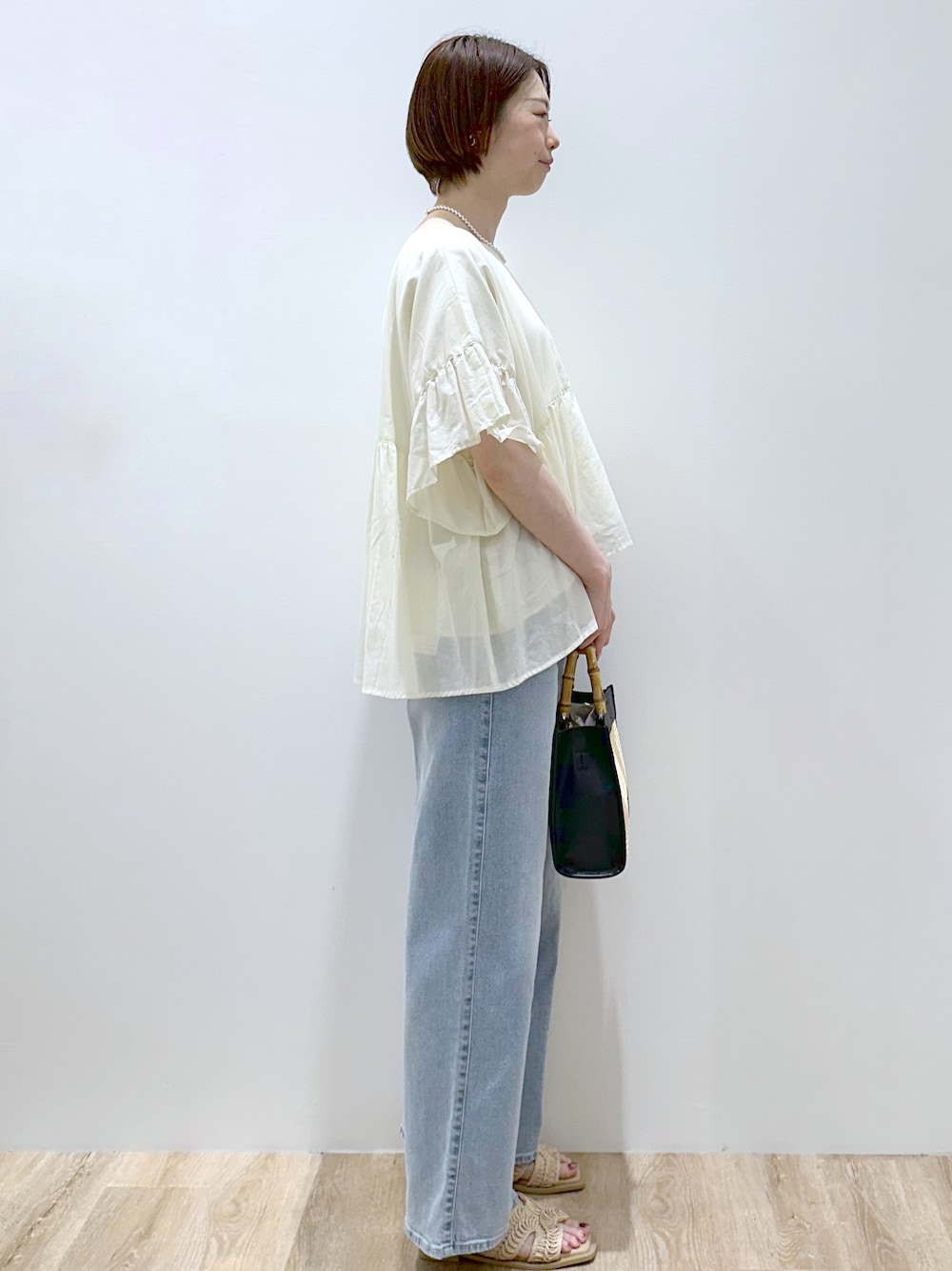 ホワイト系のシャツ/ブラウス、ブルー系のデニムパンツ、ブラック系のトートバッグを着用したレディースの春コーディネートの4枚目の写真