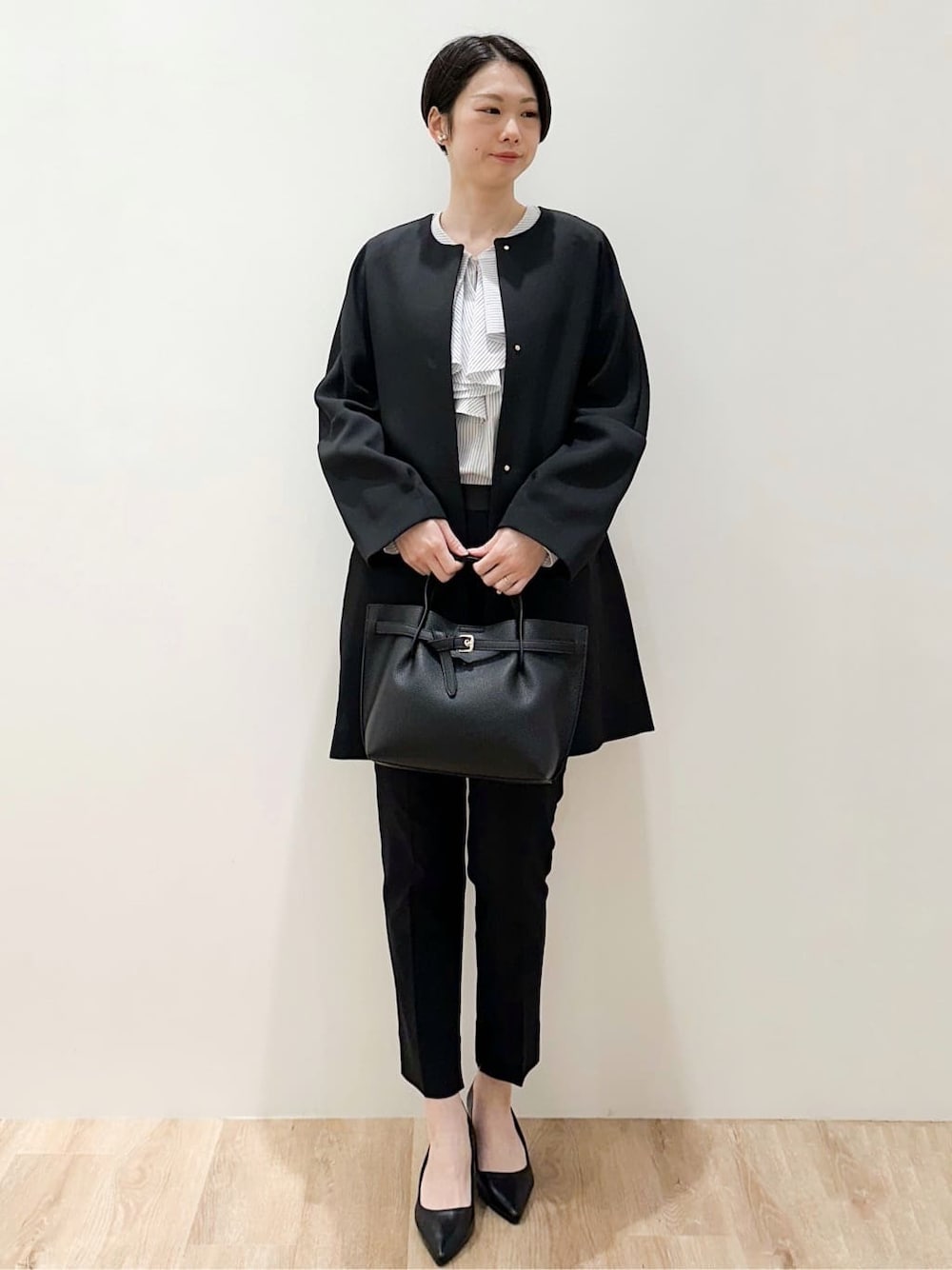 ブラック系のノーカラーコート、ホワイト系のシャツ/ブラウス、ブラック系のその他パンツを着用したレディースの冬コーディネートの2枚目の写真