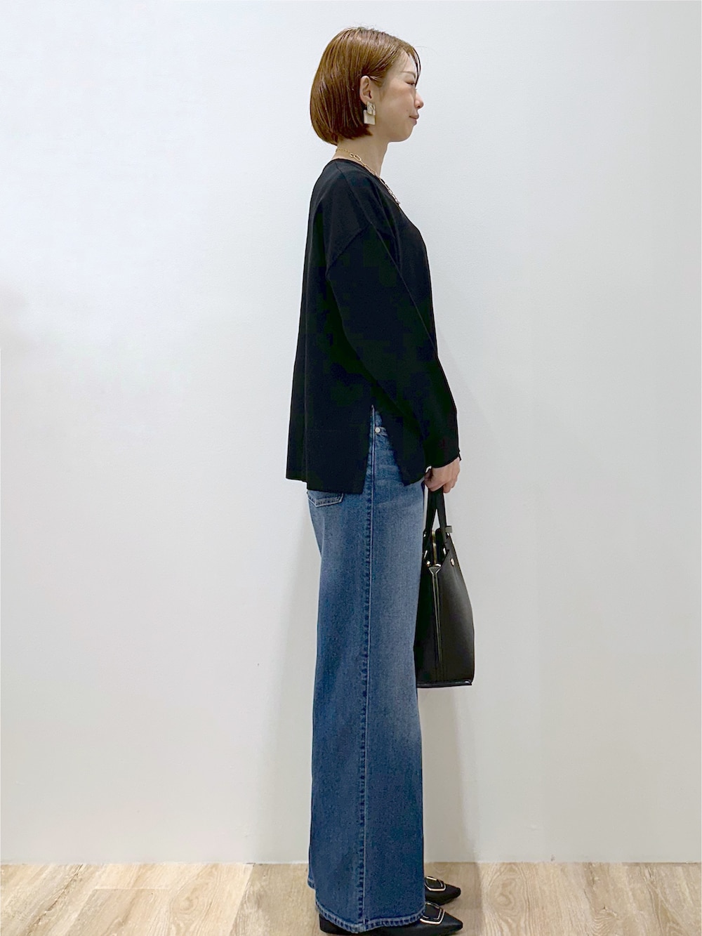 ブラック系のニット/セーター、ブルー系のデニムパンツ、ブラック系のトートバッグを着用したレディースの秋コーディネートの4枚目の写真