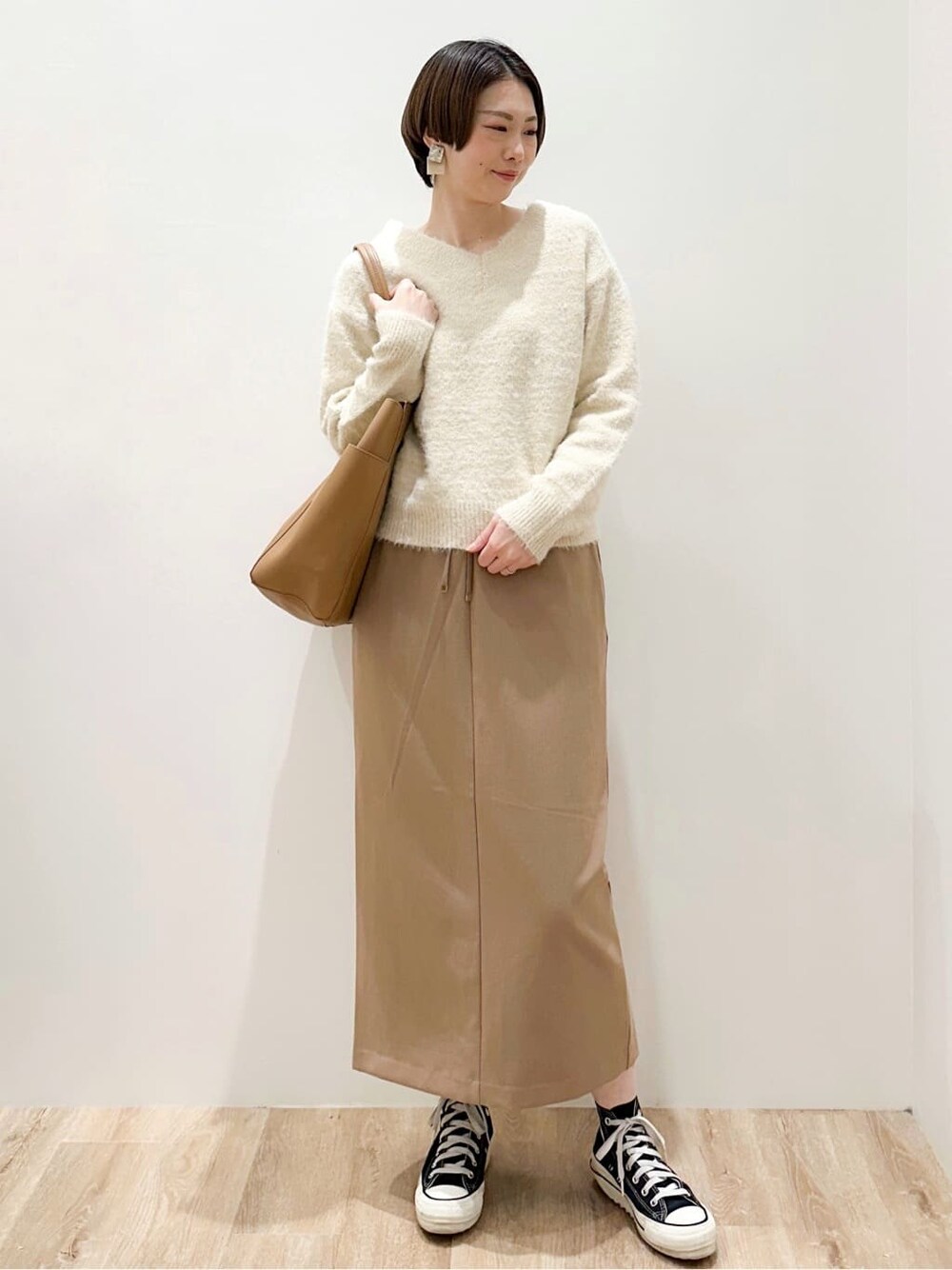 ベージュ系のニット/セーター、イエロー系のスカート、ベージュ系のトートバッグを着用したレディースの冬コーディネートの4枚目の写真